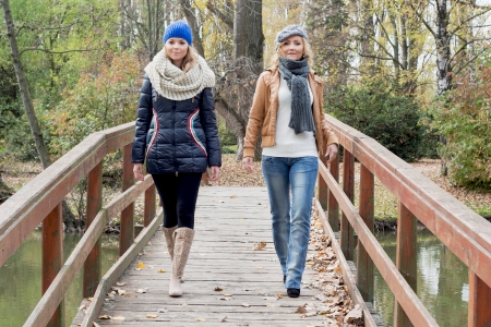Two attractive young caucasian women posing on a wooden bridge.の写真素材