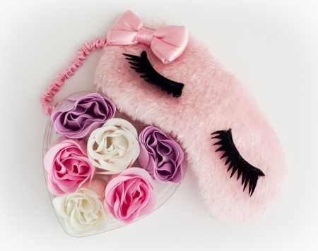 Pink sleeping mask and little heart made of fabric flowers on a white background. の写真素材