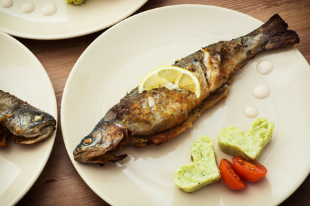 Delicious baked fish with two hearts of mashed potatoes and cherry tomatoes.の写真素材