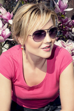 Blonde caucasian woman posing with blooming magnolia.の写真素材