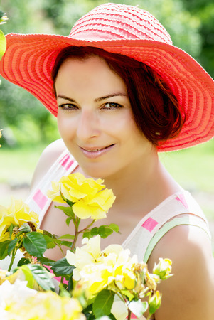 Beautiful caucasian woman in a red hat posing in the garden.の写真素材