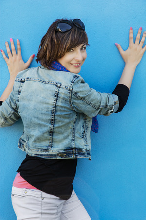Beautiful caucasian brunette posing in front of a blue wall.の写真素材