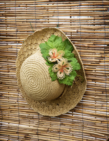 Lady straw hat with decorative flower ribbon hung on the bamboo wall.の写真素材