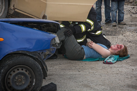 Nitra, Slovakia - September 06, 2014: Simulation of the car accident. Firefighters saving the bleeding woman from a crashed car.のeditorial素材