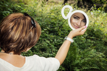 Young brunette is looking to the mirror in outdoors.の写真素材