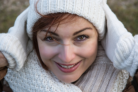 Young positive woman with white knitted cap and gloves. Beauty and fashion.の写真素材