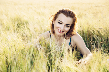 Woman in love is smoothing the wheat cobs in the field.の写真素材