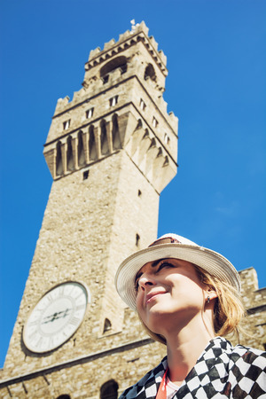 Pretty woman in hat is posing under the Palazzo Vecchio in the city Florence, Tuscany, Italy. Tourist destination.の写真素材