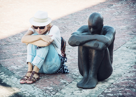 Young woman sits and imitates the pose of the iron statue. Forte di Belvedere, Florence, Italy. Young woman sits and imitates the pose of the iron statue. Forte di Belvedere, Florence, Italy.