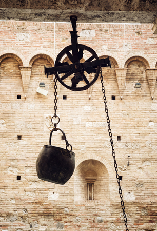 Metal bucket on a pulley hanging in the courtyard of the historic palace, Siena, Tuscany, Italy.のeditorial素材