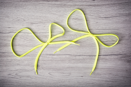 Yellow shoelaces in the ribbon shape on the wooden background.の写真素材