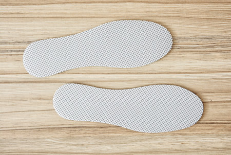 New white shoe insoles on the wooden background.