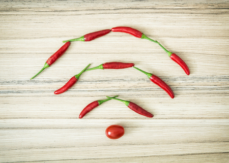 Chili peppers in the wifi symbol shape on the wooden background.の写真素材