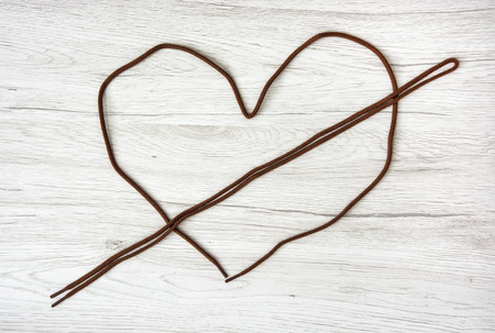 Brown shoelaces shaped in the heart on the wooden background. Valentine's day. Symbol of lovers.の写真素材