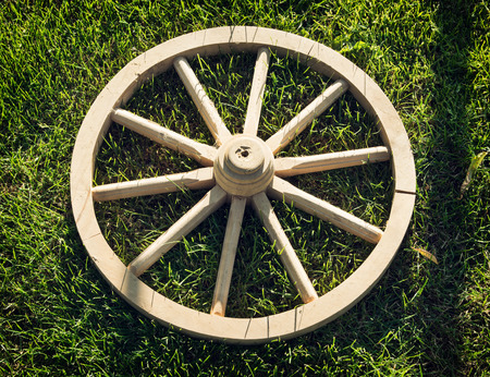 Old wooden wheel on the grass. Rural scene.の写真素材