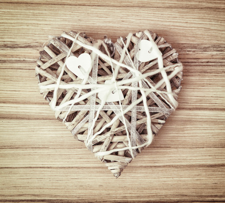Braided decorative valentine heart on the wooden background. Symbol of lovers.の写真素材