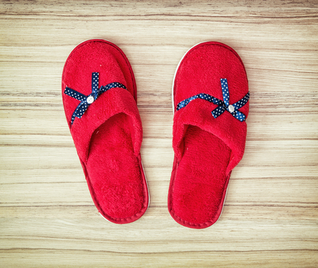 Red slippers with blue ribbon on the wooden background. Beauty and fashion. Retro style.の写真素材