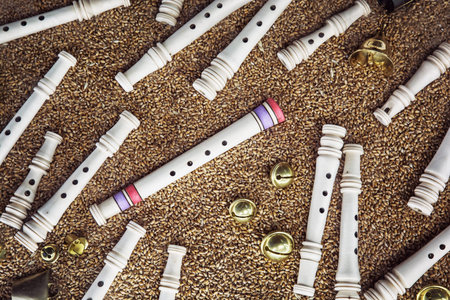Wooden whistles, brass bells and gingle bells on the grain background. Artistic objects.