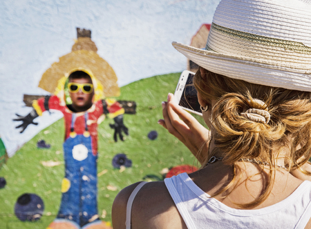 Young caucasian woman takes photo of her son in the family park. Outdoor activity.の写真素材