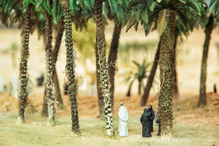 Little figurines of Arabs in the desert oasis under the palm trees. Artistic symbolic objects.の写真素材