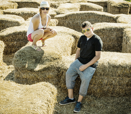 Woman with the son are sitting on the haystack. Outdoor activity.の写真素材