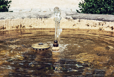 Small fountain in the park. Garden decoration. Sprayed water. Drinking water.