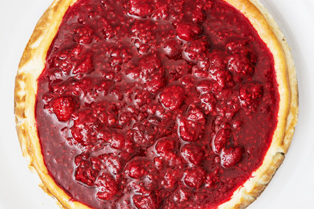 Rounded delicious cheesecake with raspberries on the plate. Sweet food. Vibrant colors. Yummy cheese...