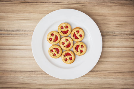 Seven round biscuits smiling faces on the white plate. Good mood. Humorous food. Tasty cookies.
