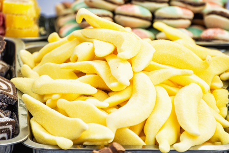 Yellow tasty licorice candies in plastic container. Sweet delight. Vibrant colors. Sweetmeats scene. Confectionery in the shop.の写真素材