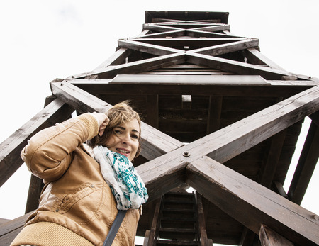 Young tourist woman posing under the big wooden lookout tower. Travelling theme. Interesting place to visit.の写真素材