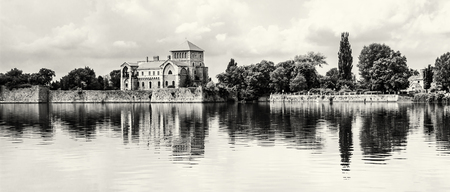 Beautiful castle with greenery and cloudy sky in Tata, Hungary. Travel destination. Architectural theme. Black and white photo. Fortress is reflected in the lake.のeditorial素材