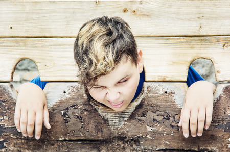 Young caucasian boy in medieval pillory. Negative emotions. Misery theme. Punishment device.の写真素材