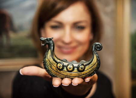 Young caucasian woman posing with little artistic wooden ship. Female portrait. Symbolic object. Positive emotions.の写真素材