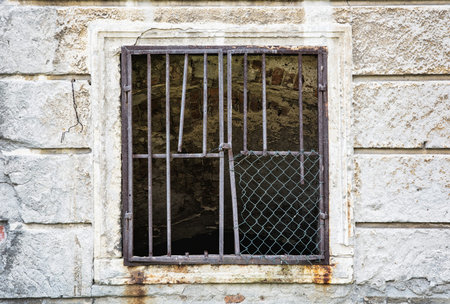 Old wall with barred window. House for demolition. Architectural element.