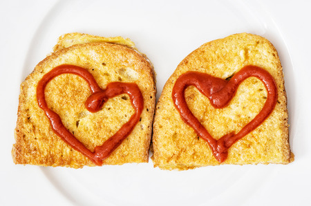 Two fried breads in the egg with hearts of ketchup on white plate. Valentine theme. Creative food. Positive emotions.の写真素材