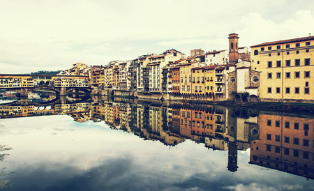 Ponte Vecchio and historical buildings are mirroring in the river Arno, Florence, Tuscany, Italy. Retro photo filter.の写真素材
