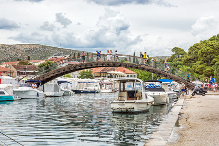 TROGIR, CROATIA â JULY 25, 2017: Many tourists are walking through the arched bridge in Trogir, Croatia, . Travel destination. Summer vacation. Illustrative editorial. Side view.のeditorial素材