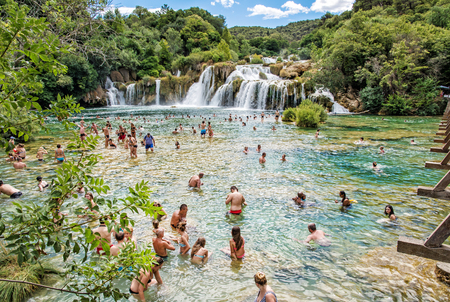 TROGIR, CROATIA â JULY 27, 2017: Many tourists are swimming in the waterfalls, Krka, Croatia, national natural park. Summer vacation. Travel destination. Illustrative editorial.のeditorial素材