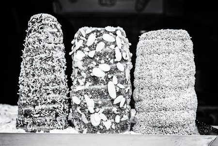 Trdelnik is a kind of spit cake. It is made from rolled dough that is wrapped around a stick, then grilled and topped with sugar and walnut mix. Black and white photo.の写真素材