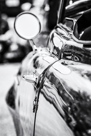 Veteran car with rear-view mirror and handle. Vintage car. Old automobile. Black and white photo.の写真素材