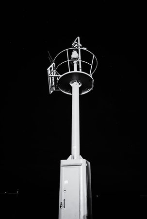 Red light beacon with night starry sky, Porec, Croatia. Safe maritime transport. Black and white...