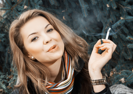 Young caucasian woman smokes a cigarette. Problems of young. Teal and orange photo filter.の写真素材