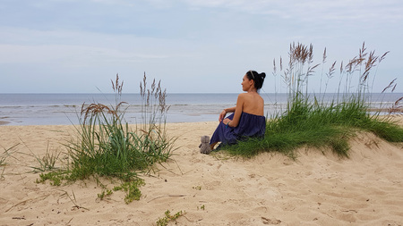 Baltic sea, woman on grassy sand dune with a soft toyの写真素材