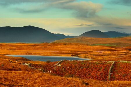 bright autumn orange colour landscape, hazy mountains, blue lake from Connemara, Galway, Irelandの写真素材