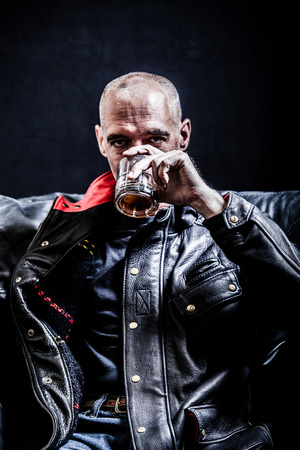 A man in a leather jacket drinking whiskeyの写真素材