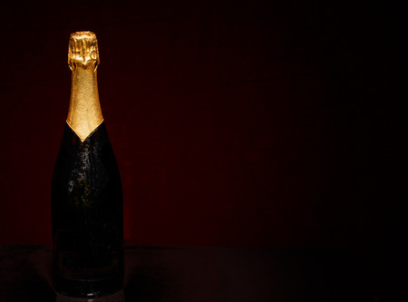 Champagne bottle on black background with red lightingの写真素材
