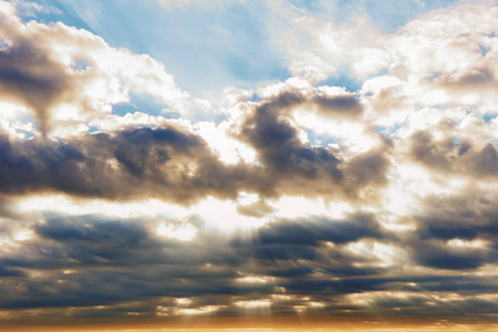 Angry clouds with the sun bursting through and patches of blue sky.の写真素材