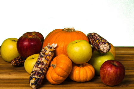 Pumpkin, green and red apples, Gourds and corn on a hardwood cutting boardの写真素材