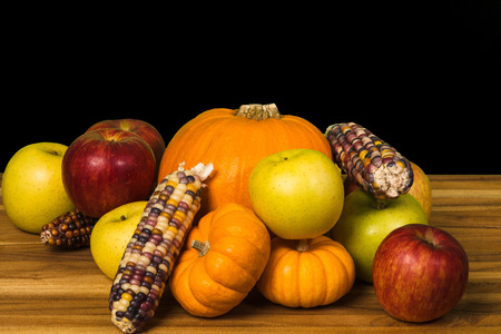 Pumpkin, green and red apples, Gourds and corn on a hardwood cutting boardの写真素材