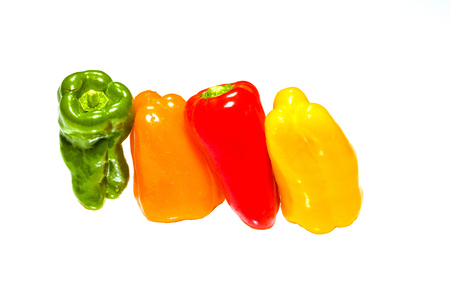 Green, Orange, Red and yellow peppers leaning against one another on a brilliant white backgroundの写真素材